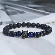 Bracelet masculin en pierres volcaniques noires et perles œil de tigre bleu avec tête de loup métallique détaillée.