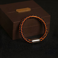 Bracelet tressé orange et noir en polyester avec fermoir métallique argenté, style unisexe.