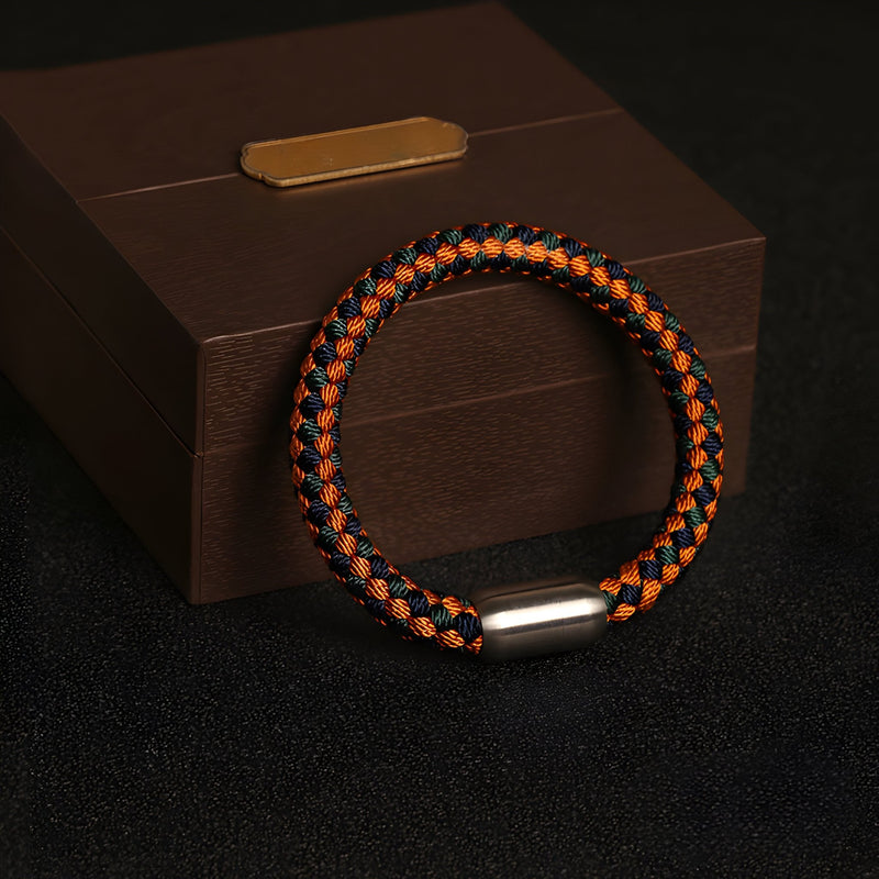 Bracelet tressé orange et noir en polyester avec fermoir métallique argenté, style unisexe.