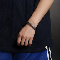 Bracelet en polyester motif tressé noir et blanc sur poignet, style unisexe.