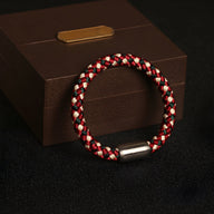 Bracelet tressé en polyester rouge, blanc et noir avec fermoir métallique argenté mat.