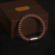 Bracelet mixte Marley tressé noir et marron avec fermoir argenté posé sur coffret marron élégant.