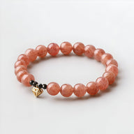 Bracelet femme perles rondes quartz rose avec pendentif cœur doré et perle noire.