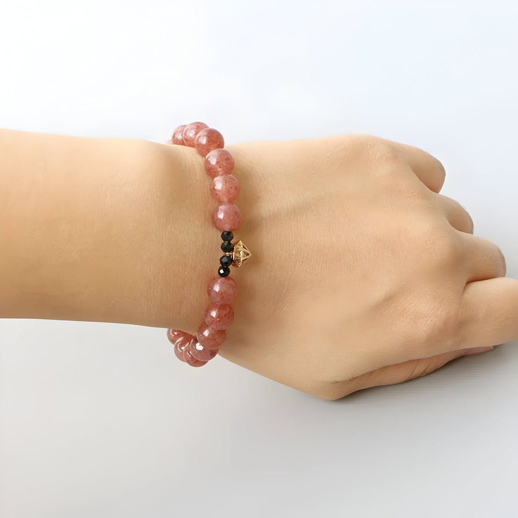 Bracelet pour femme en perles de quartz rose avec breloque noire et dorée, taille 17 cm.