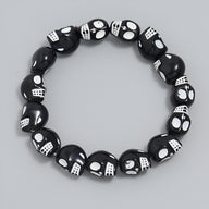 Bracelet pour homme en résine noire avec crânes blancs assemblés au style gothique.