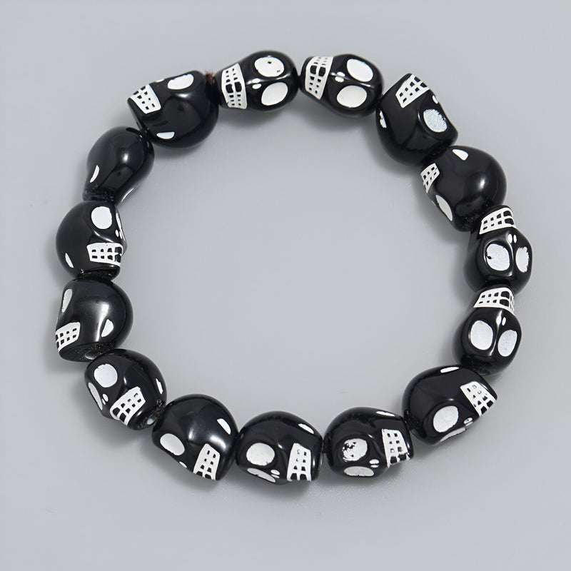 Bracelet pour homme en résine noire avec crânes blancs assemblés au style gothique.