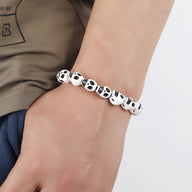 Bracelet homme en résine blanche avec crânes assemblés détaillés noirs.
