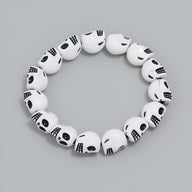 Bracelet pour homme en résine blanche avec perles en forme de crânes noirs assemblés.