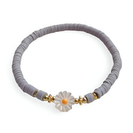 Bracelet en résine gris orné d'une marguerite blanche avec cœur jaune et perles dorées.