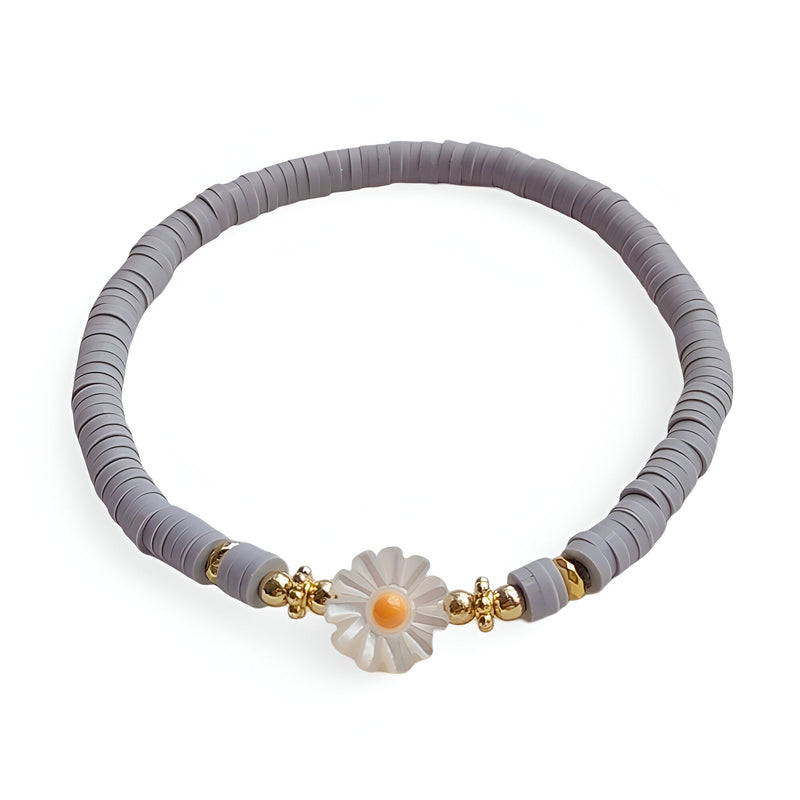 Bracelet en résine gris orné d'une marguerite blanche avec cœur jaune et perles dorées.