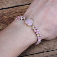 Bracelet en rhodonite rose et quartz rose avec pendentif en forme de cœur doré, style multi-rangs.