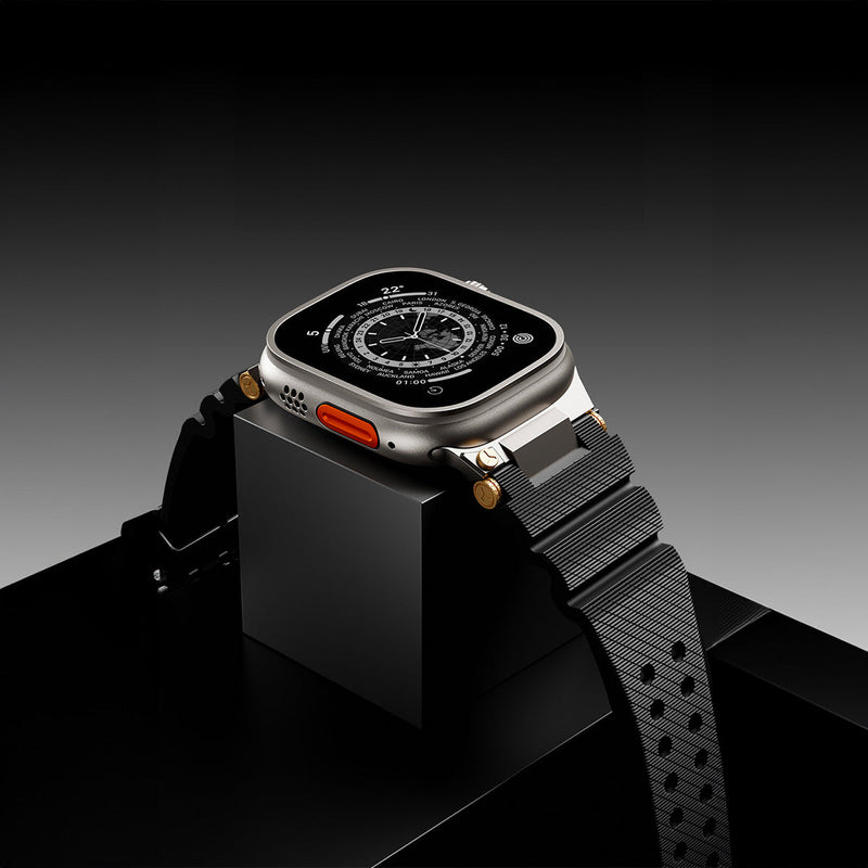 Bracelet silicone noir avec détails or et bouton orange pour Apple Watch, style technique ajustable.