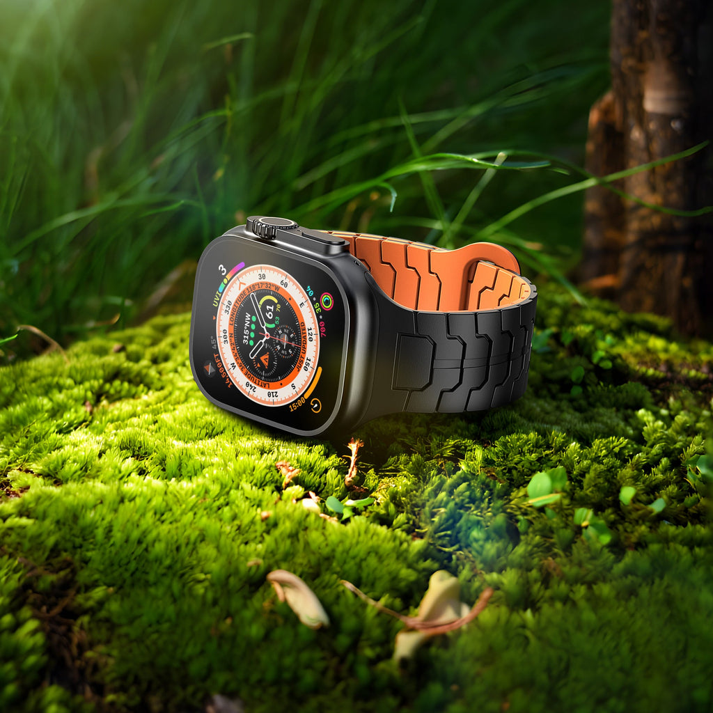 Bracelet silicone noir extérieur avec intérieur orange aspect technique pour Apple Watch sur mousse verte.