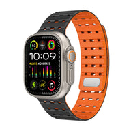 Bracelet silicone noir et orange perforé, style sportif, ajustable pour Apple Watch.