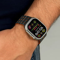 Bracelet silicone noir avec perforations orange pour Apple Watch, style sportif et ajustable.