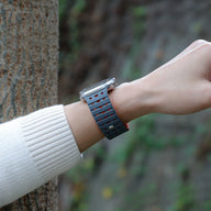 Bracelet silicone noir et orange ajouré avec fermoir argenté sur poignet, modèle Turim ajustable pour Apple Watch.