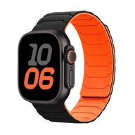 Bracelet en silicone magnétique noir à l’extérieur et orange à l’intérieur pour Apple Watch, design ajustable et résistant.