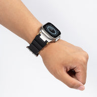 Bracelet en silicone noir pour Apple Watch avec double ardillon ajustable sur poignet mâle.