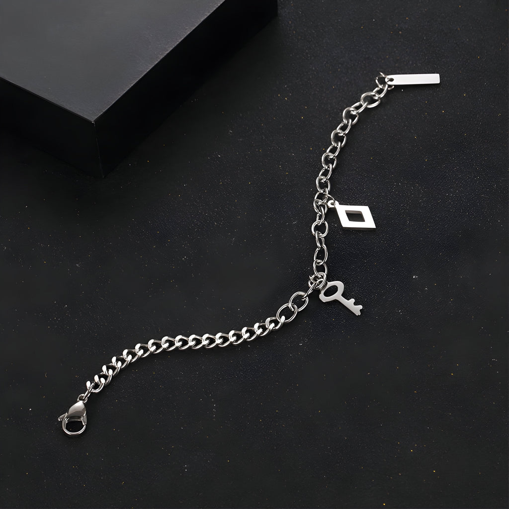 Bracelet en titane argenté à double maille avec charms clés et pendentif rectangulaire, fermoir mousqueton.