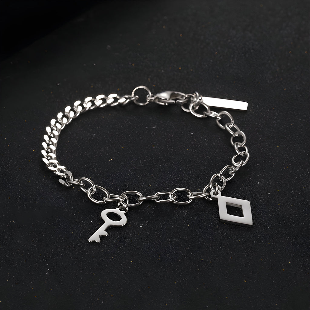 Bracelet en titane argenté à double maille avec breloques clé et losange, fermoir mousqueton.