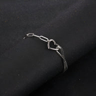 Bracelet en titane argenté avec double maille et charm cœur ajouré, design mixte.