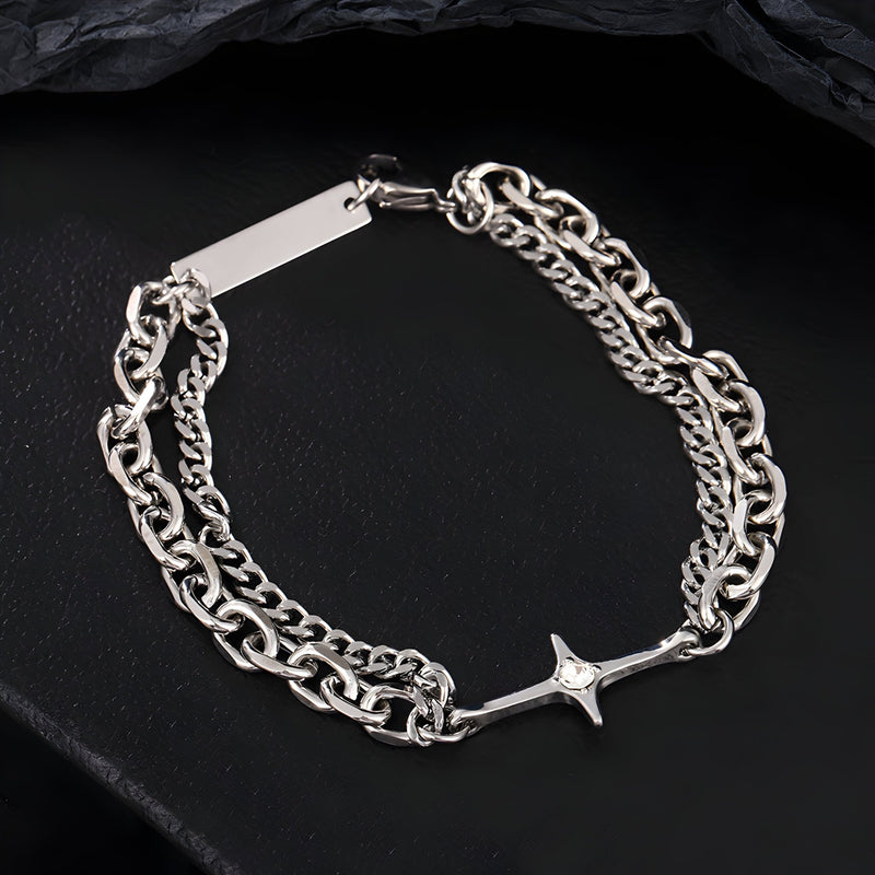 Bracelet homme double maille en titane argenté avec croix scintillante centrale sur fond noir.