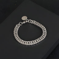 Bracelet homme en titane argenté à maille cubaine avec breloque ronde métallique.