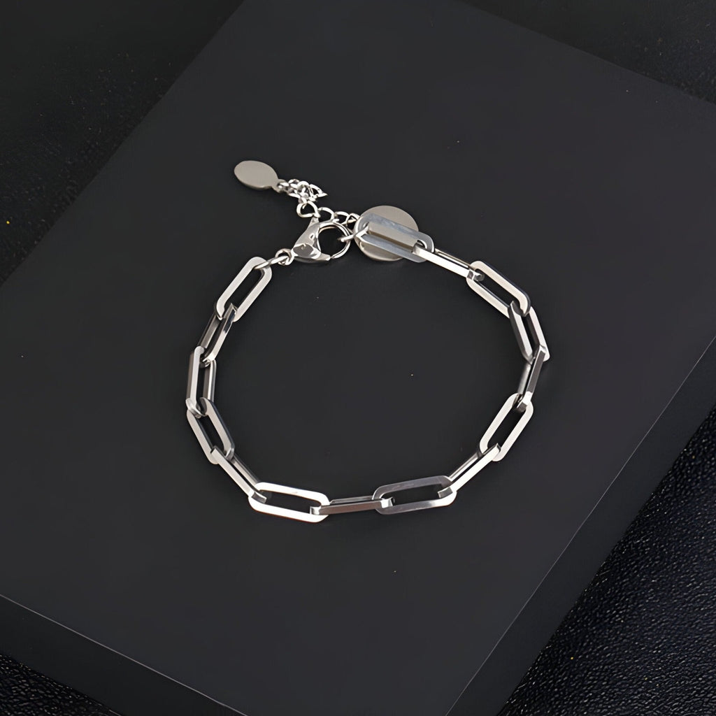 Bracelet homme en titane argenté à maille forçat avec fermoir ajustable et étiquette ronde transparente.