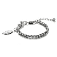 Bracelet en titane argenté avec maille spiga et charm plume élégante pour femme.