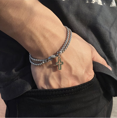 Bracelet en titane argenté à maille vénitienne avec pendentif croix chrétienne porté au poignet homme.