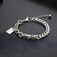 Bracelet en titane argenté pour homme avec maillons plats, plaque gravée et chaîne ajustable.