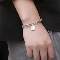 Bracelet homme en titane argenté avec maillons larges et plaque gravée rectangulaire.