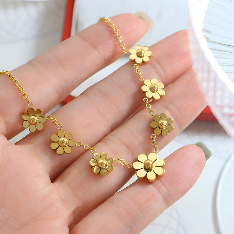 Bracelet en titane plaqué or 18 carats avec fleurs délicates et chaîne fine sur main féminine.