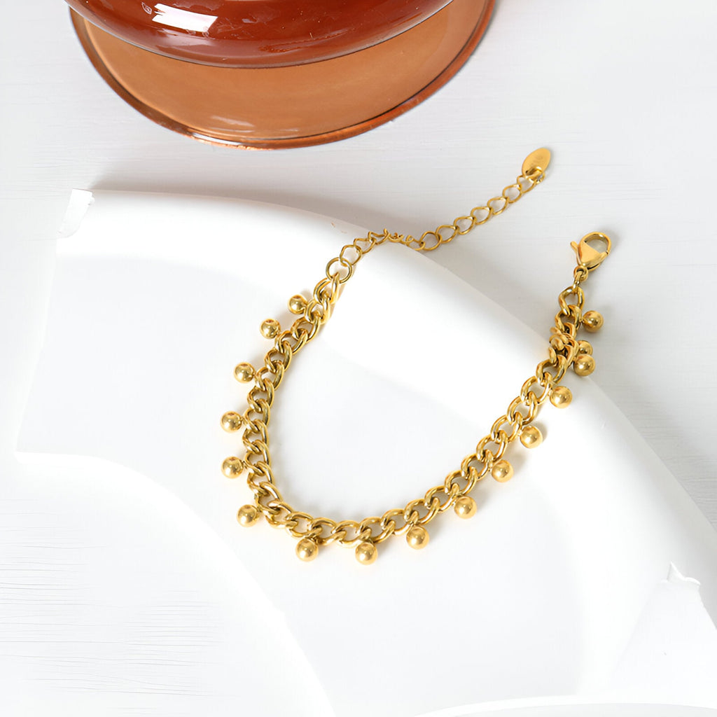 Bracelet doré en titane 18 carats avec pendentifs ronds et fine chaîne ajustable.