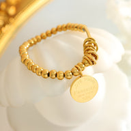 Bracelet en titane plaqué or 18 carats avec billes rondes et anneaux multiples, médaille gravée.