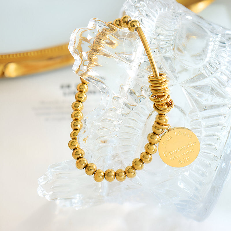 Bracelet en titane plaqué or 18 carats avec billes rondes et anneaux empilés, médaille gravée.