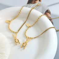 Bracelet en titane plaqué or 18 carats avec pendentif lapin stylisé, chaîne fine à maillons ronds.