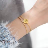 Bracelet fin en titane plaqué or 18 carats avec médaillon rond à motif géométrique, style délicat.