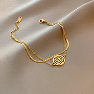 Bracelet en titane plaqué or 18 carats avec médaillon rond à motif géométrique, chaîne fine et fermoir mousqueton.