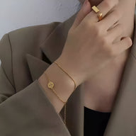 Bracelet fin en titane plaqué or 18 carats avec médaillon géométrique rond porté au poignet.