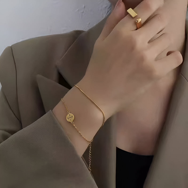 Bracelet fin en titane plaqué or 18 carats avec médaillon géométrique rond porté au poignet.