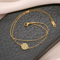 Bracelet fin en titane plaqué or 18 carats avec médaillon rond motif géométrique et chaîne délicate.