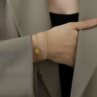 Bracelet fin en titane plaqué or 18 carats avec médaillon géométrique rond porté au poignet.