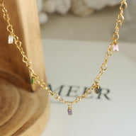 Bracelet fin en titane plaqué or 18 carats avec petites pierres de zircon rose, vert et violet suspendues.