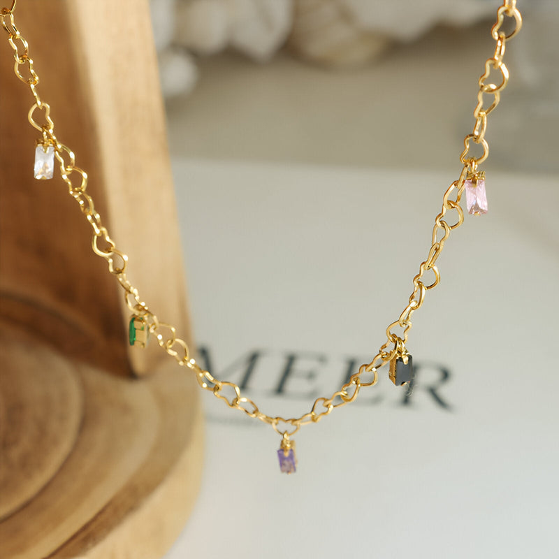 Bracelet fin en titane plaqué or 18 carats avec petites pierres de zircon rose, vert et violet suspendues.