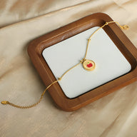 Bracelet fin en titane plaqué or 18 carats avec pendentif rond à motif pomme rouge et blanche.