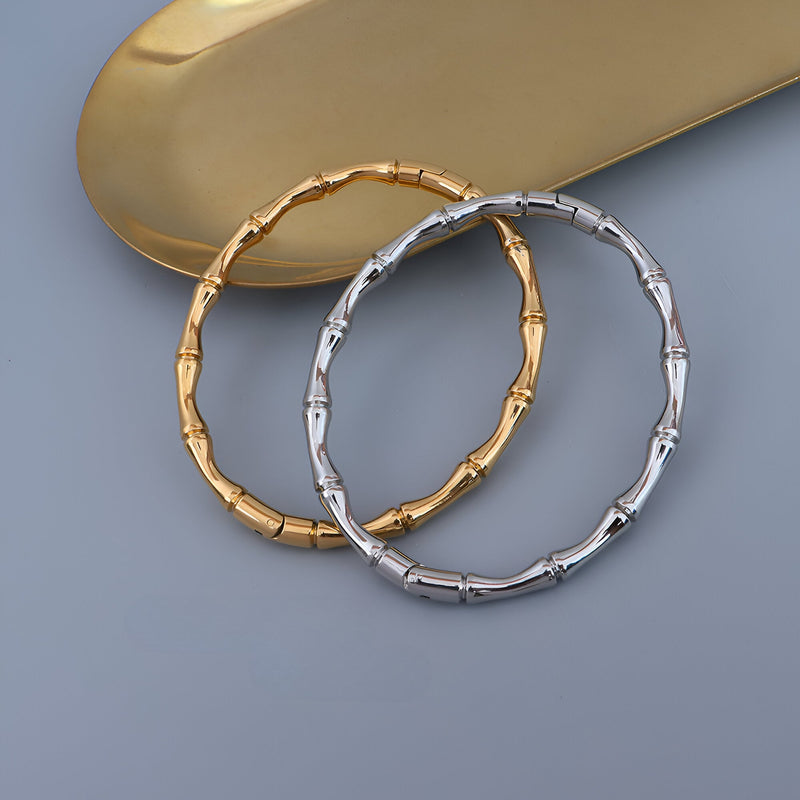 Bracelet bambou en titane plaqué or 18 carats couleur or et argent brillant sur fond gris.