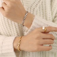 Bracelet en titane plaqué or 18 carats à maillons larges et bracelet en titane argenté à maillons larges, porté sur poignet.