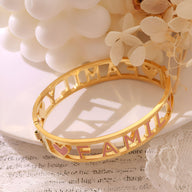 Bracelet rigide en titane plaqué or 18 carats avec découpe mots "Family" style minimaliste.