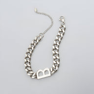 Bracelet chaîne en titane argenté avec lettre "B" ajourée et fermoir mousqueton.